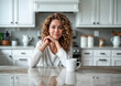 © Наталья Лазарева - beautiful woman with cup of coffee,smiling dreamily at kitchen table,with curly hair below her shoulders,ideal for lifestyle blogs and advertising home decor, demonstrating atmosphere of cozy kitchen