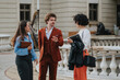 © qunica.com - Three young professionals conversing in an outdoor courtyard, showcasing teamwork, collaboration, and modern business attire against a historic building backdrop.