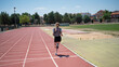 © C&A - Rear view of young female athlete running on a track field