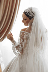 Wall Mural - A bride is wearing a white dress and a tiara. She is standing in front of a curtain