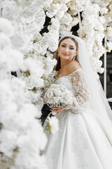 Wall Mural - A bride is posing for a picture in front of a white archway. She is wearing a white dress and a veil