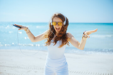 Wall Mural - happy female on ocean coast dancing and listening to music