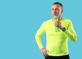 Wall Mural - Portrait of sporty middle-aged man with water bottle on blue background