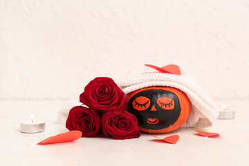 Wall Mural - Pumpkin with drawn face, paper hearts, roses and clay mask on light background