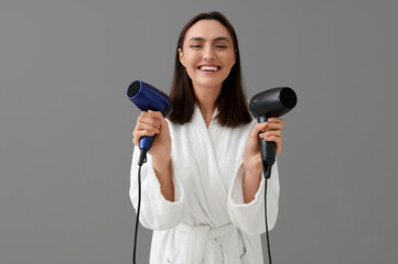 Wall Mural - Beautiful young woman with hair dryers on grey background