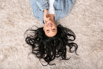 Canvas Print - Beautiful young woman with dark wavy hair lying on carpet in living room