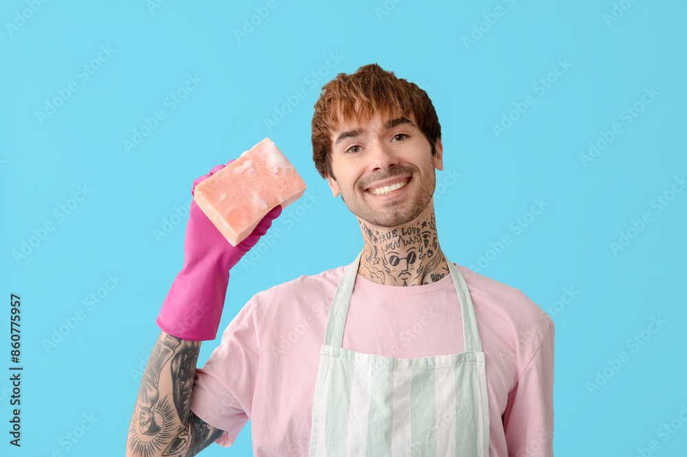 Young tattooed man with sponge on blue background