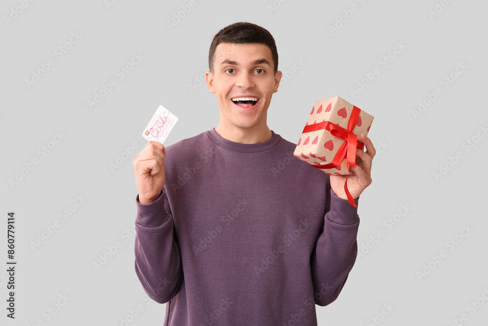 Handsome man with gift card and present on white background