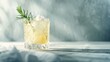 © Ibad - A glass tumbler with a pale yellow cocktail and a sprig of rosemary