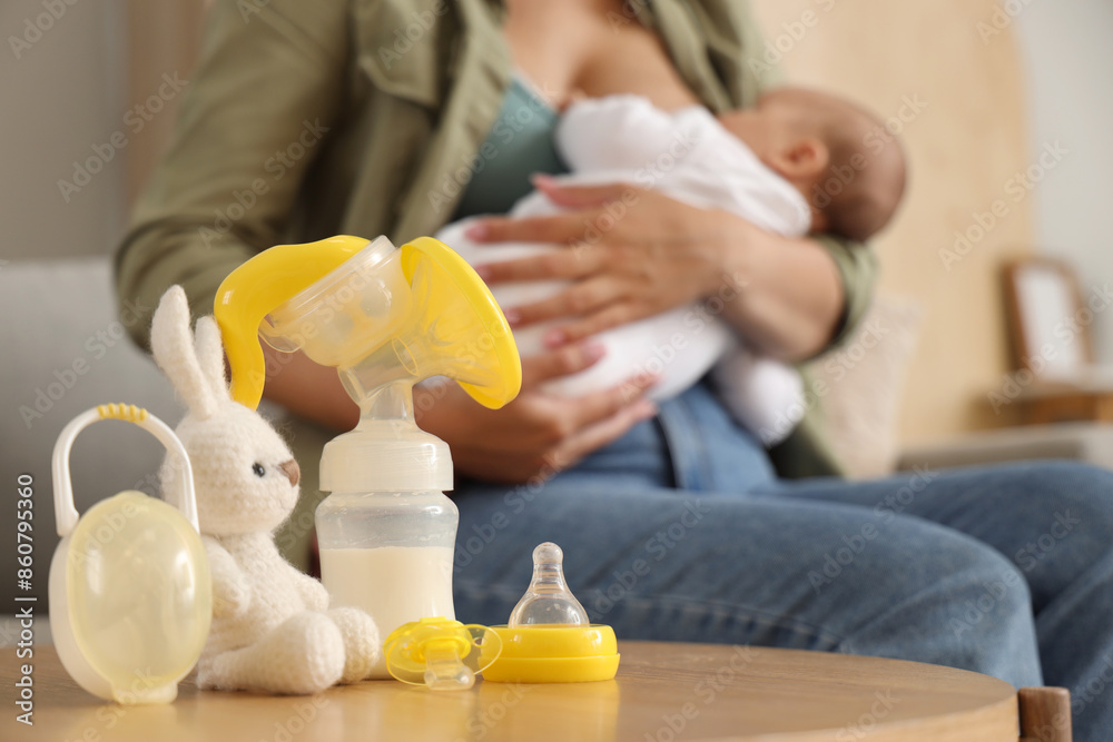 Breast pump with baby pacifier and toy on table in room, closeup