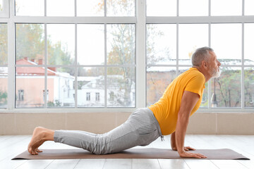 Wall Mural - Sporty mature man doing yoga on mat in gym