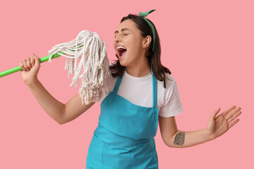 Wall Mural - Pretty young woman having fun with mop on pink background