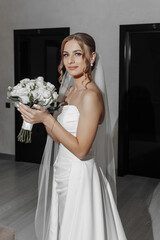 Wall Mural - A woman in a white dress holding a bouquet of flowers. She is smiling and looking at the camera