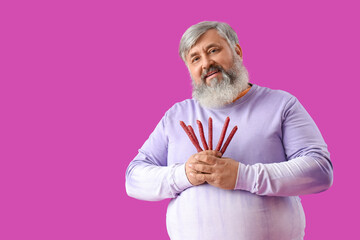 Wall Mural - Mature man with tasty sausages on purple background