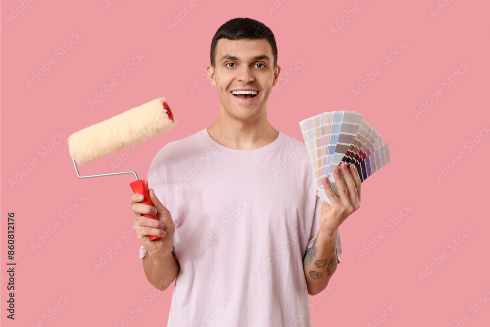Young man with color swatches and paint roller on pink background