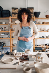 Portrait of potter standing at pottery studio and looking at camera.