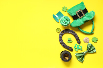 Wall Mural - Leprechaun hat with horseshoe, bow tie and cupcake on yellow background. St. Patrick's Day celebration