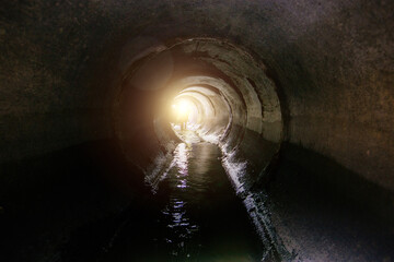 Canvas Print - Dirty sewage flowing in round underground sewer tunnel