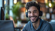 © Jhon - A man is smiling and providing courteous and attentive service in a call center office, working in front of a laptop with a soft dark tone.