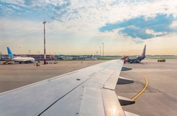 View of airplane wing, blue skies and green land during landing. Airplane window view.