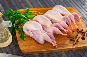 Wall Mural - Uncooked quails on wooden board with parsley and black pepper. Home kitchen, preparing food.