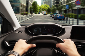 Wall Mural - Driving car, view from driver's seat. Man holding hands on steering wheel, closeup