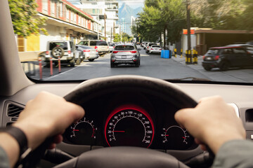 Canvas Print - Driving car, view from driver's seat. Man holding hands on steering wheel, closeup