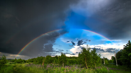 Rainbow over rural landscape after thunderstorm. Two rainbows in the sky after a thunderstorm