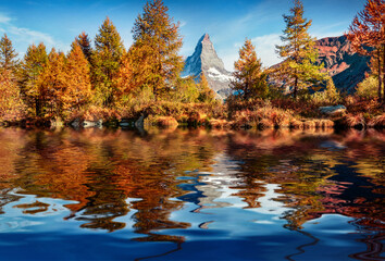 Wall Mural - Colorful larch trees and Matterhorn peak reflected in the calm waters of Grindjisee lake. Breathtaking autumn scene of Swiss Alps, Zermatt resort location, Switzerland, Europe. Travel the world..