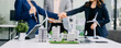 © Nuttapong punna - Group of diverse multiethnic businesspeople standing neare table looking at model of building from residential project. Green business company and Solar Energy Environment city