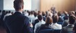 © StockKing - A speaker delivering a presentation at a corporate Business Conference with an audience in the conference hall; a Business and Entrepreneurship event with copy space image.