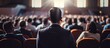 © StockKing - Speaker presenting at business and entrepreneurship symposium with copy space image of audience in conference hall, including a rear view of an unidentified participant.