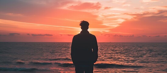 Wall Mural - Silhouette of human in the distance against the background of the sky and the sea at sunset. Copy space image. Place for adding text or design