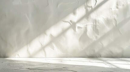 A white wall in a room with light coming through a window casting shadows