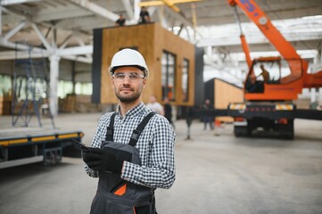 Wall Mural - A worker controls the process of loading a modular house onto a truck. Transportation and delivery concept