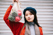 © Westend61 - Confident young woman holding mesh bag with vegetables