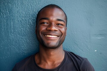 Wall Mural - Portrait of a blissful afro-american man in his 30s smiling at the camera while standing against plain cyclorama studio wall