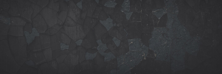 Dark wide panoramic background. Peeling paint on a concrete wall. Faded dark texture of old cracked flaking paint. Weathered rough painted surface with patterns of cracks. Shaded background for design