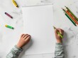 © Philipp - Top view of a child drawing on blank paper with vibrant colored crayons, representing creativity and learning.