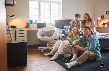 close up of teenage girls and boys at home in bedroom together playing computer games together