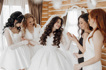 Wall Mural - A group of women are gathered around a bride, who is wearing a white dress. The women are smiling and seem to be enjoying the moment