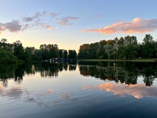 Wall Mural - purple clouds reflection on the lake surface, trees silhouettes reflections on the water surface, twilights lake in the park, natural colors, very calm and peaceful