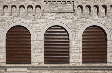 Rolling metal door of warehouse. Grunge interior background with brick wall and three arched shutter doors.