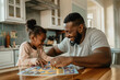 © Татьяна Евдокимова - Father and daughter are enjoying quality time together, laughing and playing a board game in their kitchen