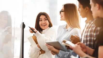 Poster - A group of diverse zoomers standing in front of a whiteboard, engaged in a discussion or presentation. The people appear focused and are actively listening or participating in the discussion.
