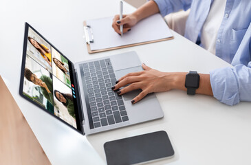 Poster - A woman is seated at a white desk with a laptop in front of her. She is using one hand to navigate the laptop while the other is resting on the desk. The laptop screen displays a video conference
