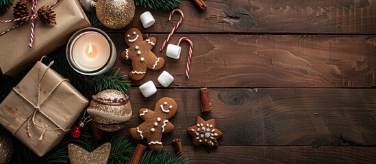 Poster - Top view of a festive setting with cocoa, marshmallow, gingerbread man, candles, and gift box on a dark wooden backdrop, ideal for a copy space image.