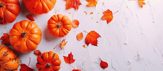 Poster - Top view of autumn-themed decorative pumpkins and fall leaves on a white table, creating a festive backdrop for a Fall Thanksgiving or Halloween greeting card with copy space image.