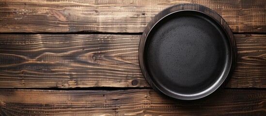 Poster - Black plate on wooden table with copy space image.