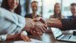 © keetazalay - A handshake between a businessman and businesswoman in a modern office, sealing a successful deal, with colleagues smiling in the background and laptops and documents on the table, showcasing